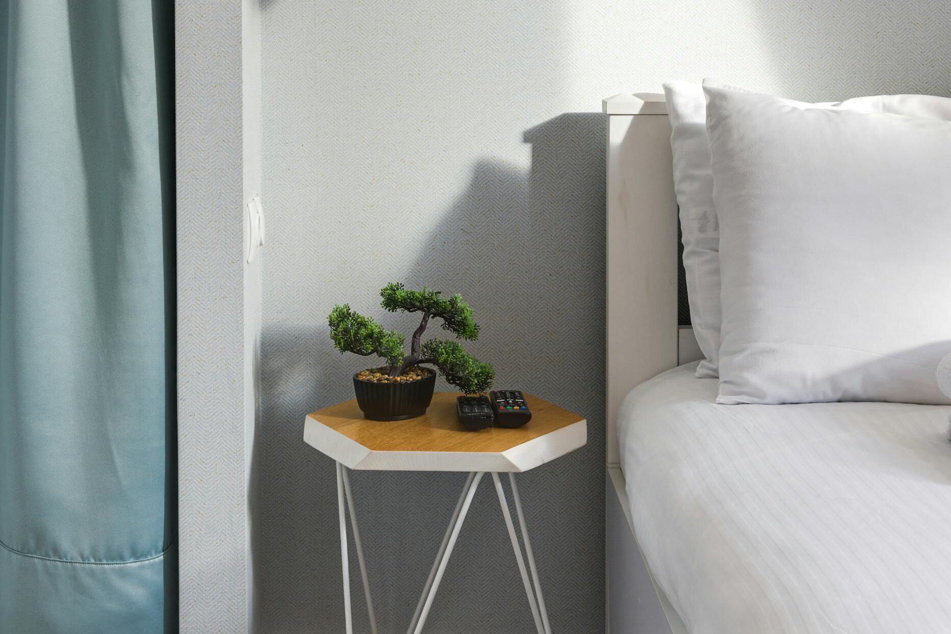 Modern bedroom with a geometric lamp, decorative table, and bonsai plant for a minimalist aesthetic.